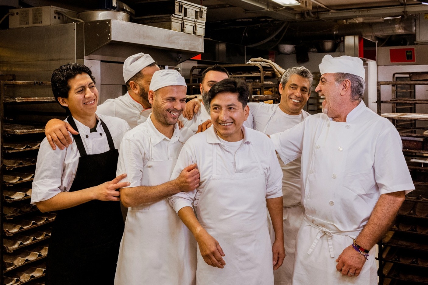 A team of 7 chefs hanging out in the kitchen together.