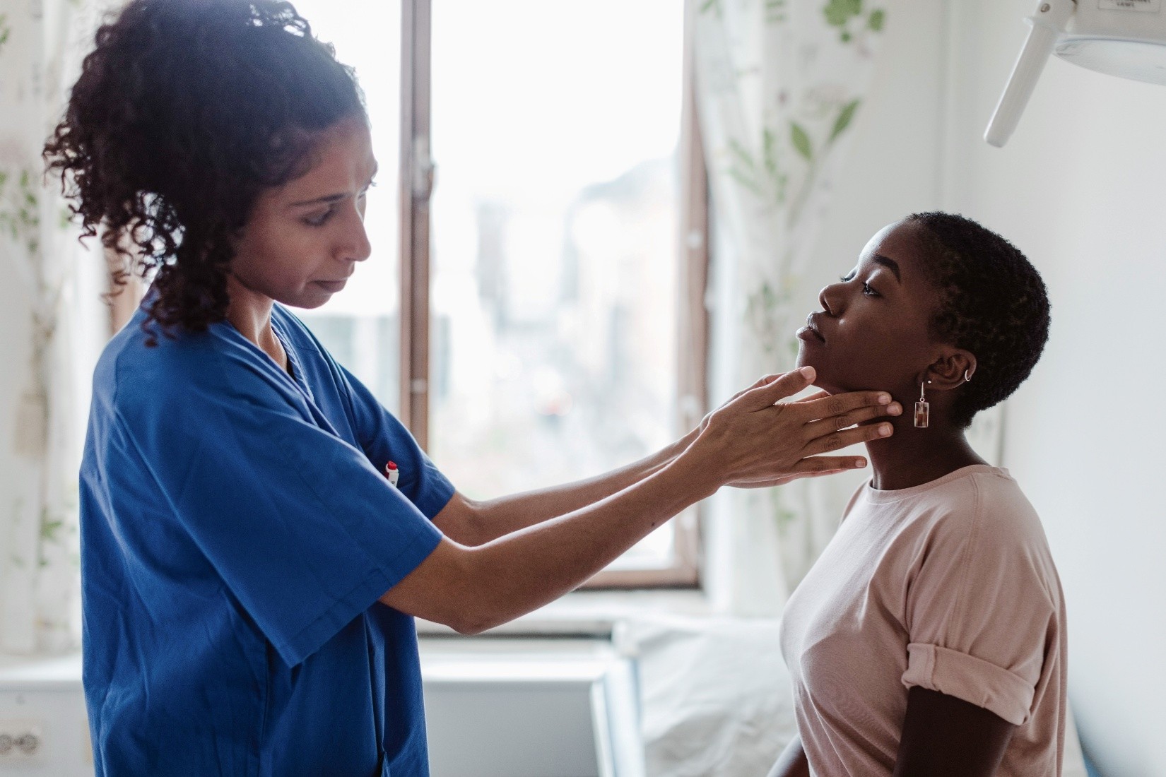 A nurse checking a patient's thyroid area.