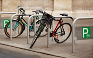 two bikes parked at public bike racks on a city sidewalk