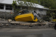 Image of a small yellow boat crashed into a shoreline and other debris in the aftermath of a tsunami