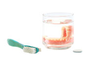 dentures in a glass with brush