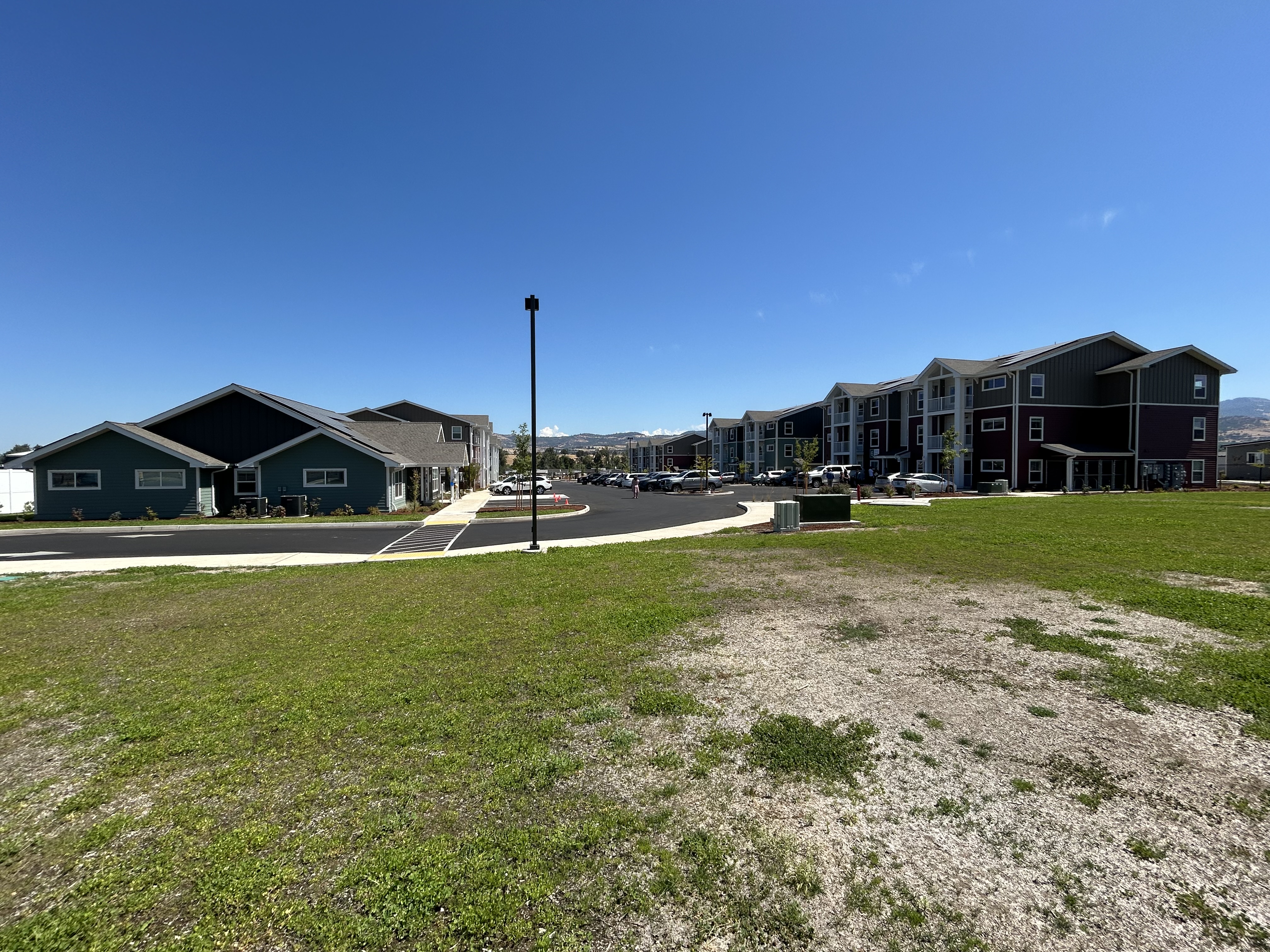photo of an apartment complex with multiple buildings in front of a green lawn