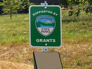 Supported by Grants sign on a post in a field with trees