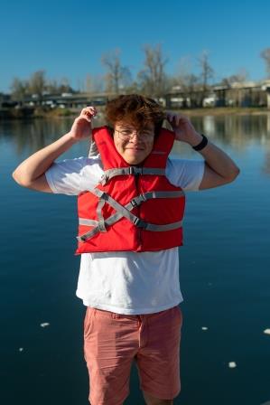 Image of a youth with a life jacket not buckled correctly and rises too high above the ears