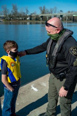 Marine deputy greeting a young boater wearing a life jacket