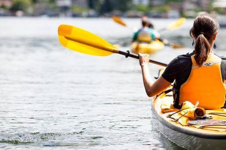 Paddler with a yellow life jacket and paddle in a yellow kayak