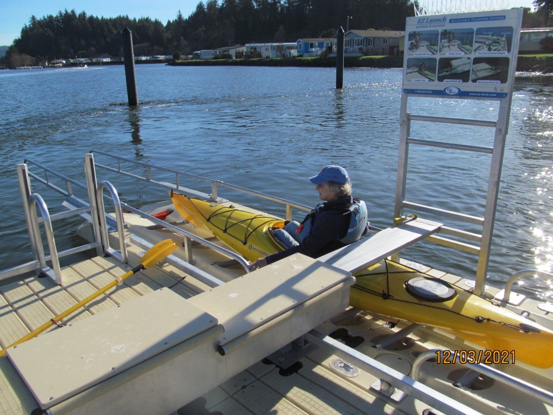 Ocean kayak preparing to launch from an ADA transfer bench at the Port of Alsea