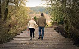 Couple walking across a wooden bridge carying a chuck-it dog toy
