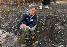 man empties bottle of water into a creek