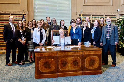 Governor Kotek signs SB1561 at desk with key people from Natural Resource agencies
