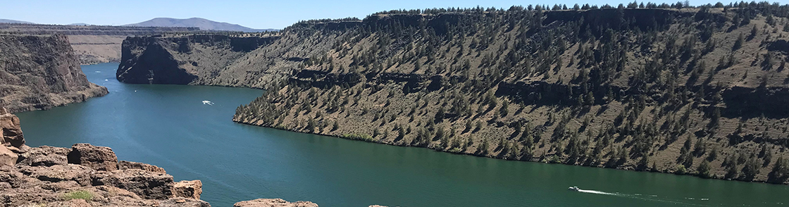 Looking into the Cove Palisades with river and boats below steep rocky cliffs
