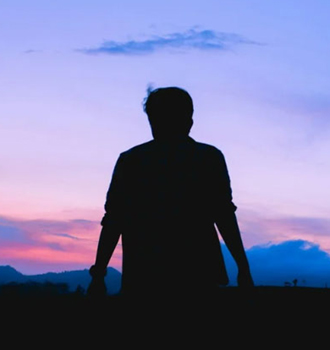 silhouette of a person looking into a sunset or sunrise