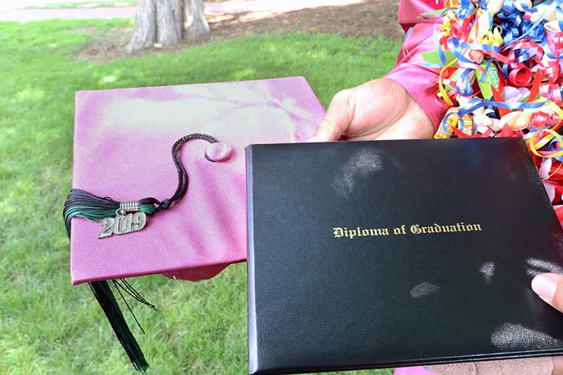 student holding graduation cap and diploma