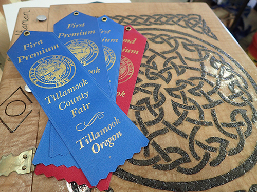 three blue and one red ribbon from Tillamook County Fair on decorative piece of wood.JPG