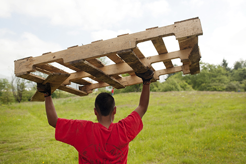 man carries wood pallet above head