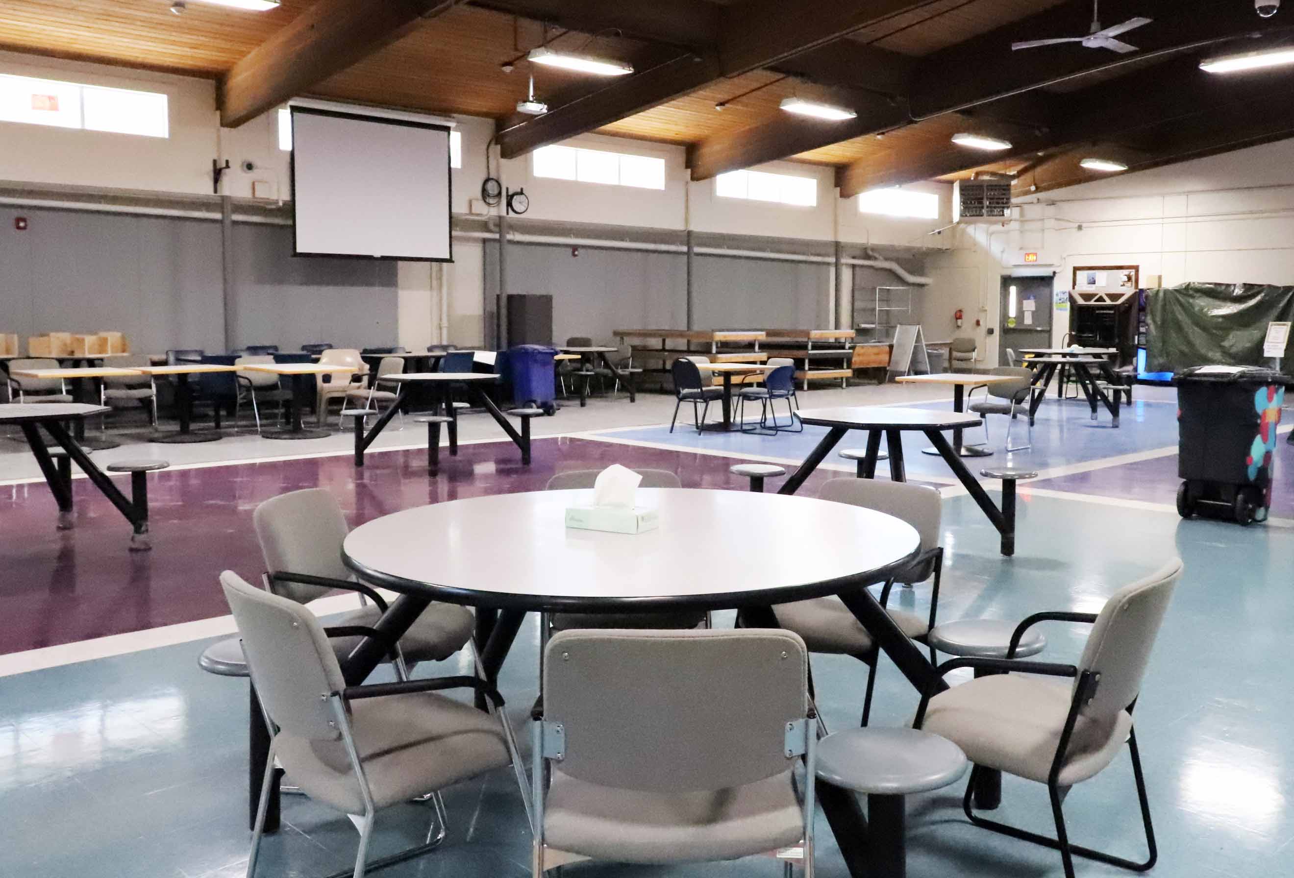 Large room with round tables spread around the room, each table with several chairs around it