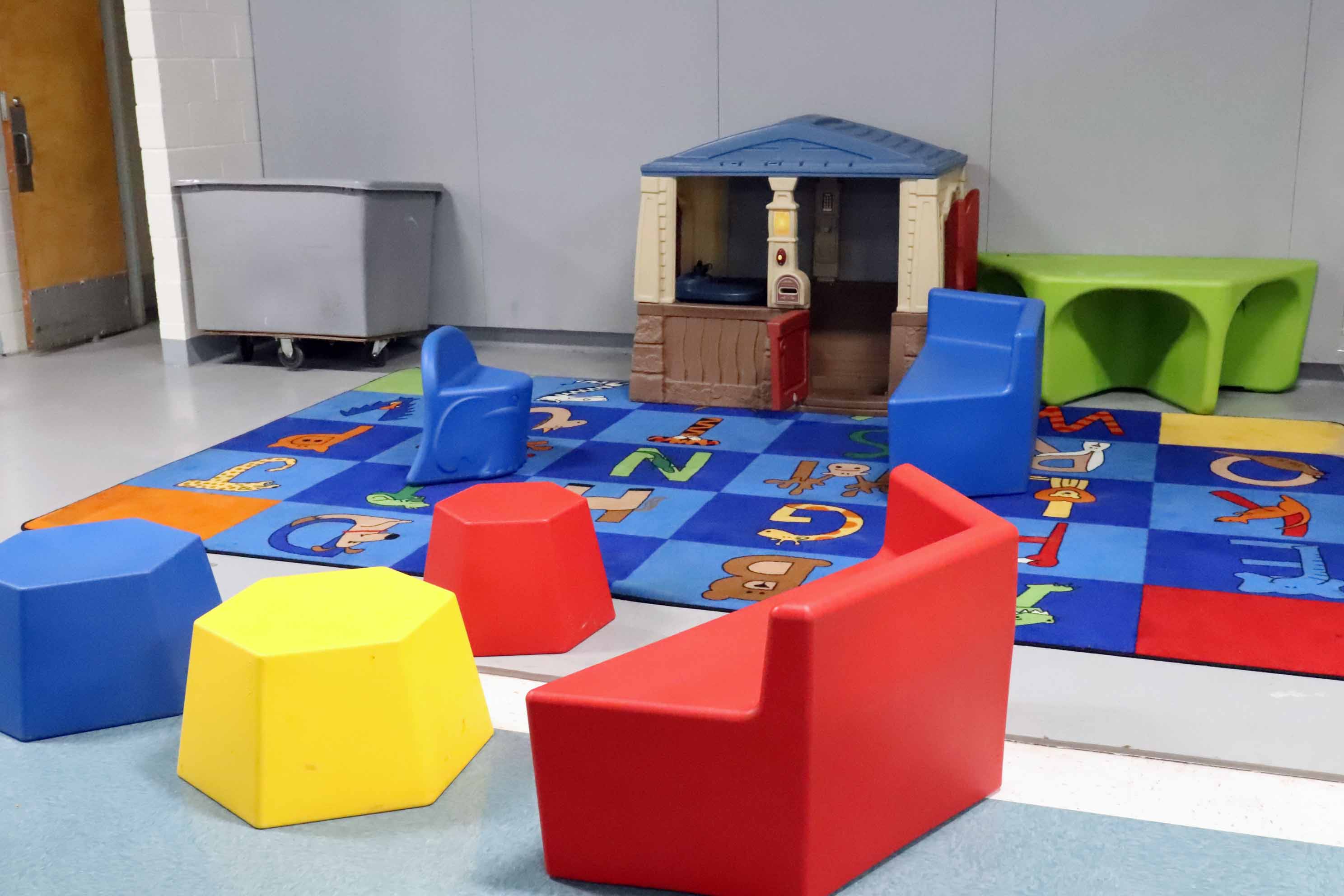 Children play area, several kid chairs with a small playhouse and an alphabet rug