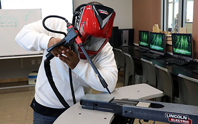 youth wearing helmet uses welding simulation machine
