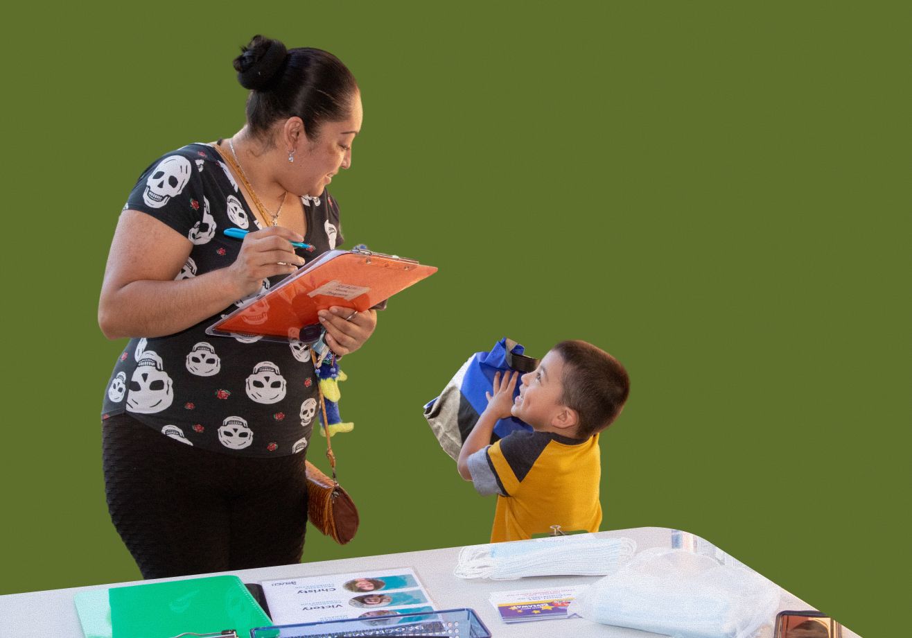 Child standing next to a woman while she fills out a form on a clipboard