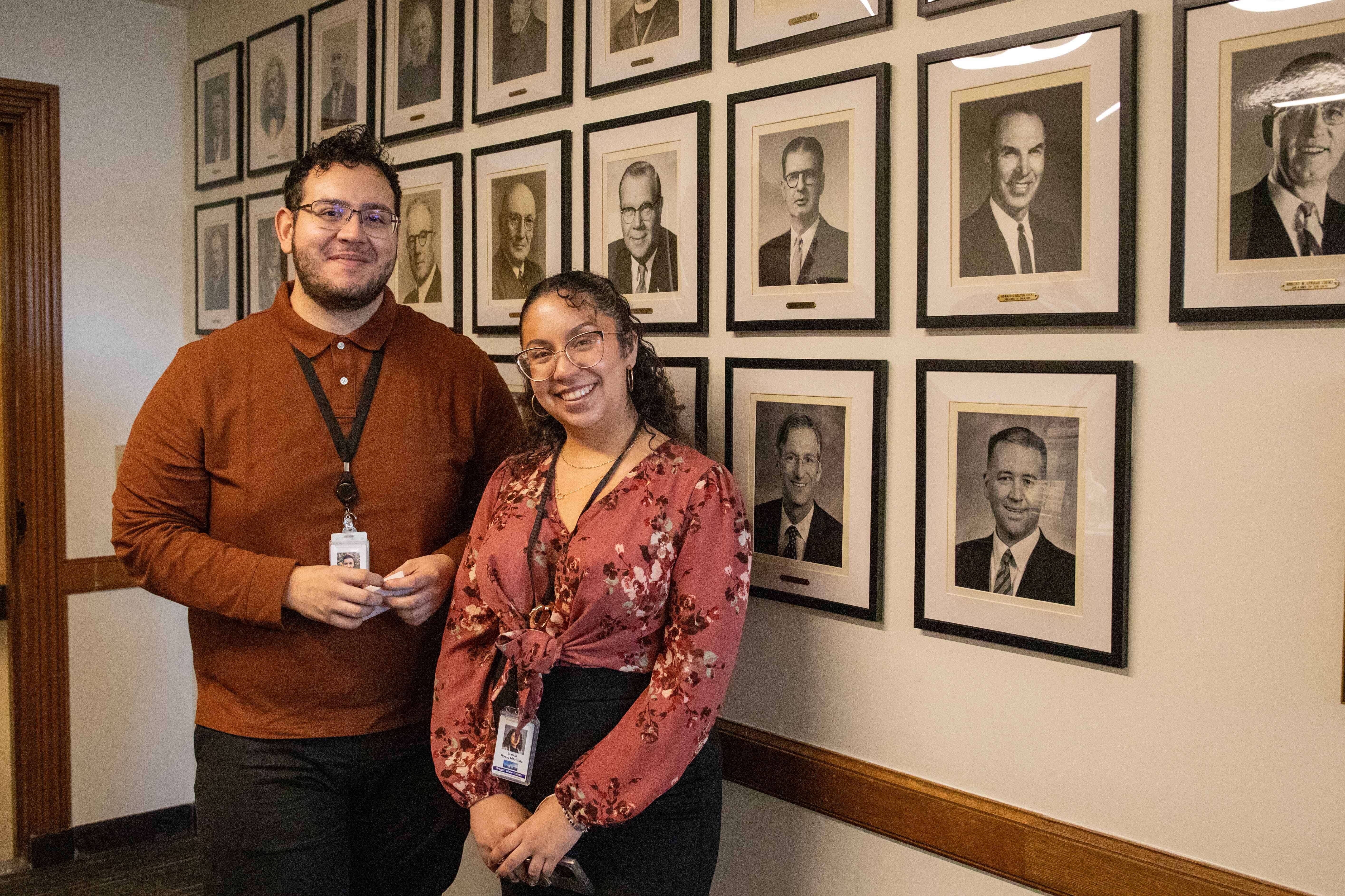 Photo of staff next to wall of historical Treasurer photos