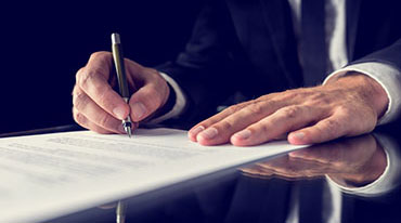 Photograph of hands signing a document