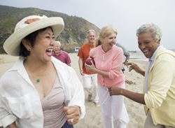 Group of active older adults laughing and playing on a beach