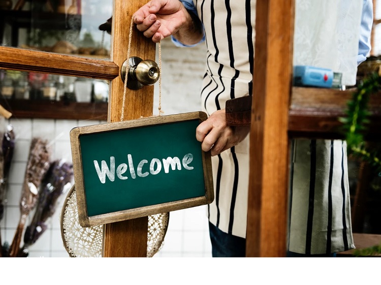 Welcome sign on door with hands either placing or removing sign